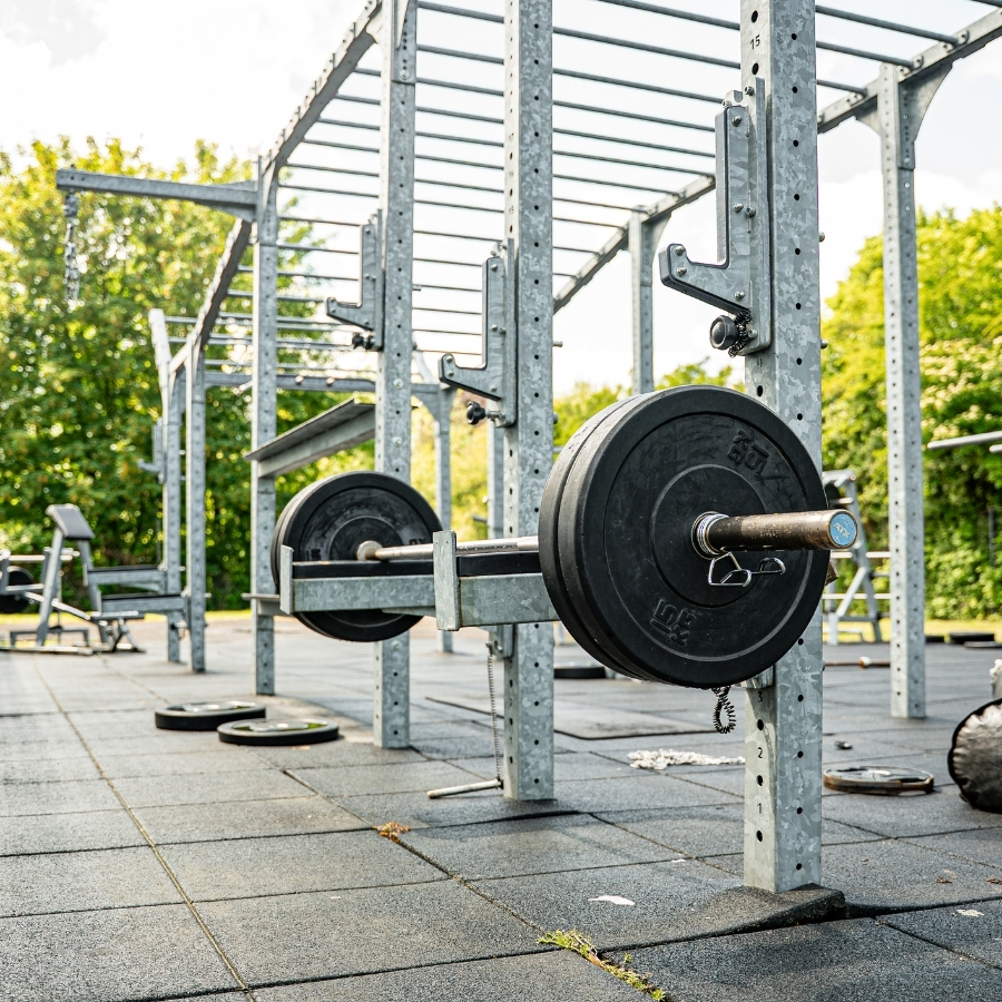 Langhantel mit Gewichtsscheiben im Squat Rack des Outdoor Bereichs bei Limitless Herten